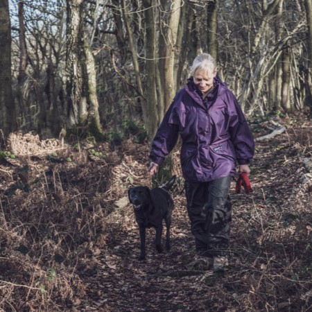 Paramo marketing - person walking through a forest with dog in purple Paramo clothing